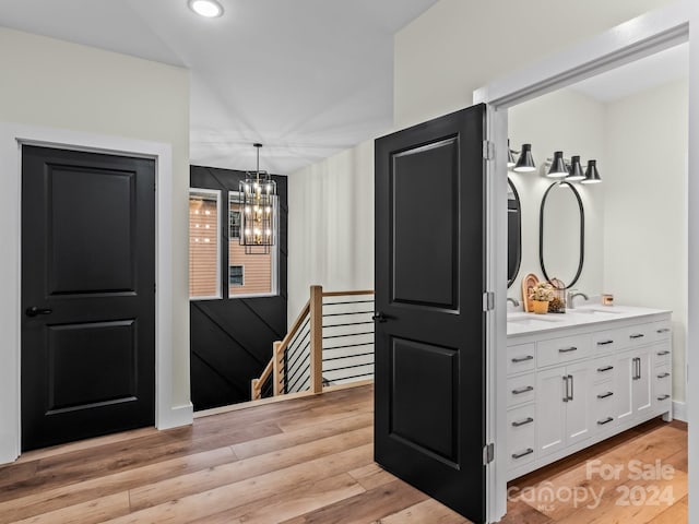 interior space with an inviting chandelier, sink, light hardwood / wood-style flooring, decorative light fixtures, and white cabinetry