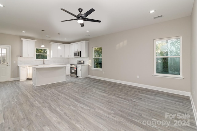 kitchen with a wealth of natural light, white cabinetry, pendant lighting, and stainless steel appliances