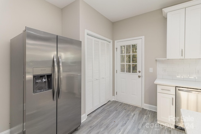 kitchen with white cabinets, light wood-type flooring, stainless steel appliances, and tasteful backsplash