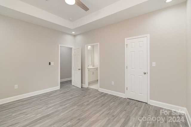 unfurnished bedroom with ensuite bath, ceiling fan, and light hardwood / wood-style floors