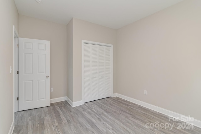 unfurnished bedroom with light hardwood / wood-style flooring and a closet