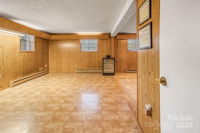 basement with wood walls, a baseboard radiator, and a textured ceiling