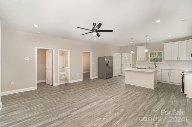 kitchen with hanging light fixtures, a center island, light wood-type flooring, and stainless steel fridge