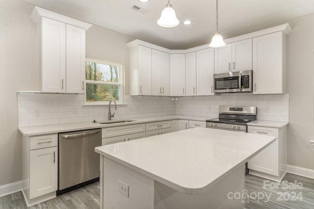 kitchen with white cabinets, pendant lighting, backsplash, and stainless steel appliances