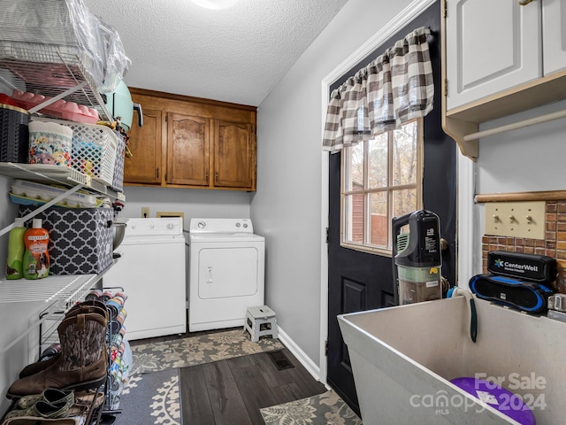 clothes washing area featuring cabinets, a textured ceiling, hardwood / wood-style flooring, and washer and clothes dryer