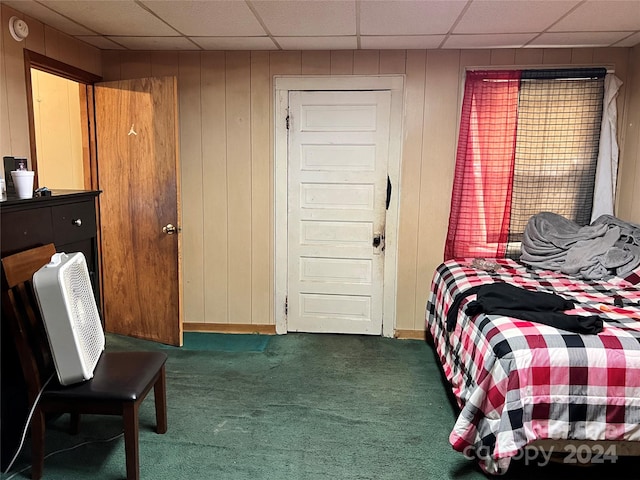 carpeted bedroom featuring wood walls and a paneled ceiling