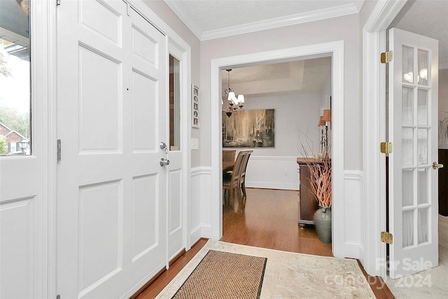 interior space with hardwood / wood-style floors, a textured ceiling, an inviting chandelier, and ornamental molding