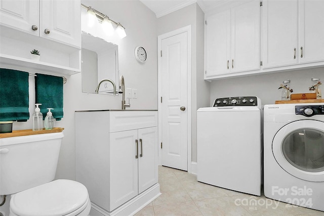 washroom featuring crown molding, light tile patterned flooring, washing machine and dryer, and sink