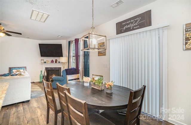 dining area featuring ceiling fan, wood-type flooring, and a premium fireplace