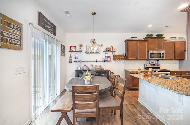 kitchen with sink, hanging light fixtures, light stone countertops, dark hardwood / wood-style flooring, and stainless steel appliances