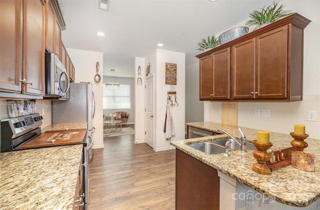 kitchen with sink, appliances with stainless steel finishes, tasteful backsplash, light hardwood / wood-style floors, and light stone counters