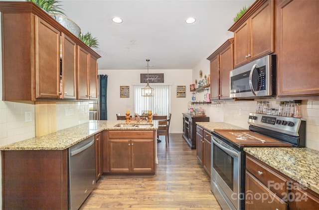 kitchen featuring kitchen peninsula, stainless steel appliances, decorative light fixtures, an inviting chandelier, and light hardwood / wood-style floors