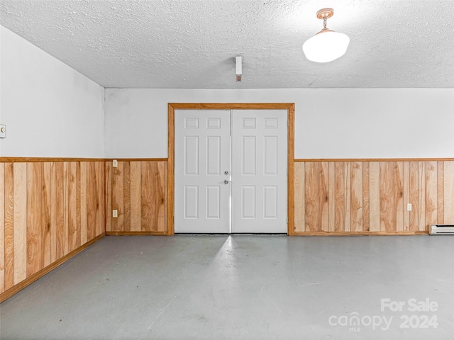 garage featuring a baseboard heating unit and wooden walls