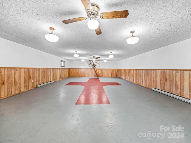 interior space featuring wood walls, ceiling fan, and a baseboard heating unit