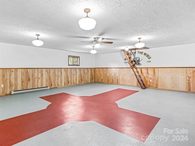 interior space featuring a textured ceiling, a baseboard radiator, ceiling fan, and wood walls