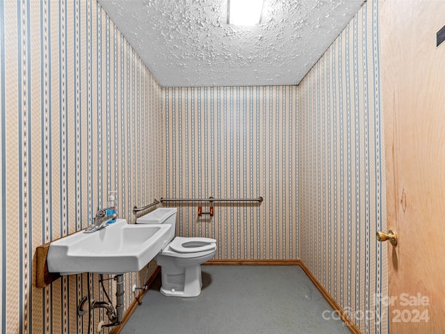 bathroom with sink, toilet, and a textured ceiling