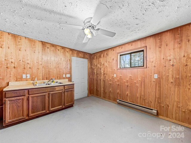 interior space featuring wood walls, sink, ceiling fan, a textured ceiling, and baseboard heating