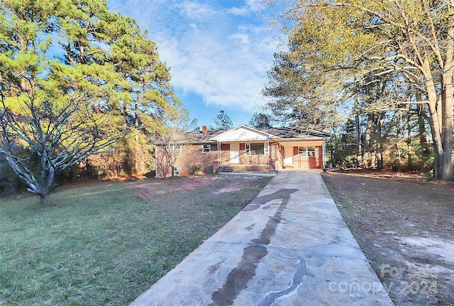 ranch-style home featuring a carport, covered porch, and a front yard