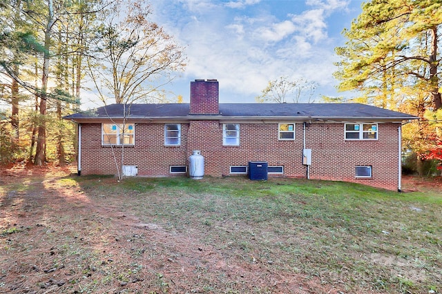 rear view of property featuring a lawn and central AC