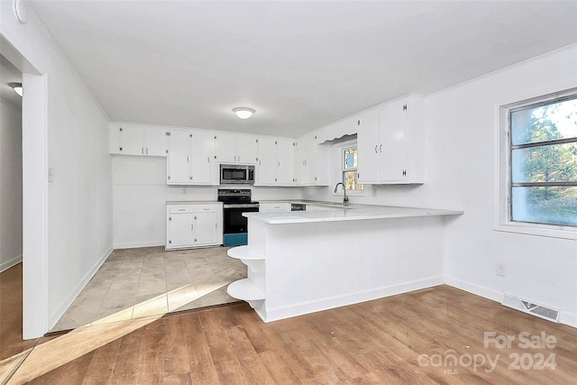 kitchen with white cabinetry, black electric range oven, kitchen peninsula, plenty of natural light, and light wood-type flooring