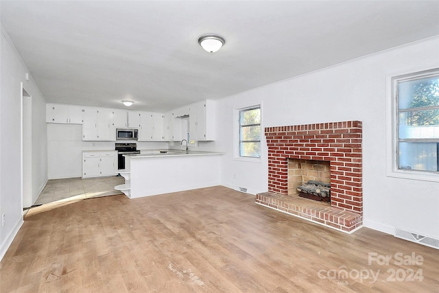 unfurnished living room featuring a fireplace, light wood-type flooring, and sink