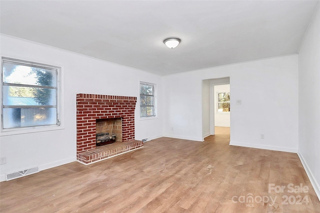 unfurnished living room with light hardwood / wood-style flooring and a brick fireplace