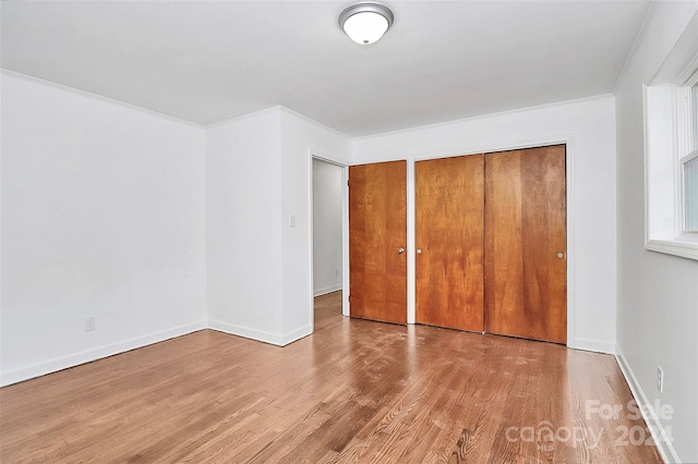 unfurnished bedroom featuring light hardwood / wood-style floors, a closet, and crown molding