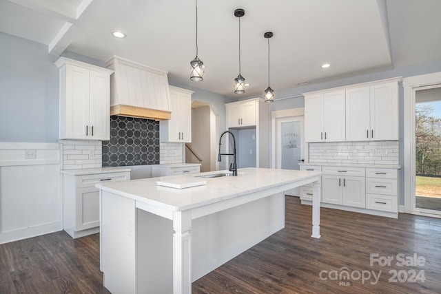 kitchen featuring white cabinetry, dark hardwood / wood-style flooring, a kitchen island with sink, and decorative light fixtures