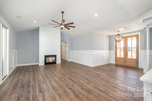 unfurnished living room with french doors, dark wood-type flooring, vaulted ceiling, ceiling fan, and a large fireplace