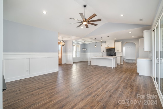 unfurnished living room featuring dark hardwood / wood-style floors, ceiling fan with notable chandelier, sink, and vaulted ceiling