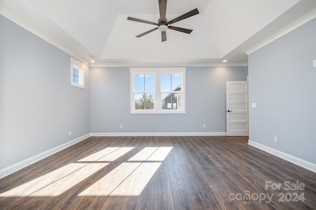 empty room featuring dark wood-type flooring, a tray ceiling, and ceiling fan