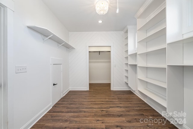 spacious closet with dark hardwood / wood-style floors and a notable chandelier