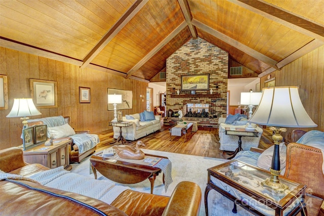 living room featuring hardwood / wood-style floors, wood ceiling, vaulted ceiling with beams, a brick fireplace, and wooden walls