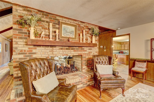 living area with a textured ceiling, hardwood / wood-style floors, and wooden walls