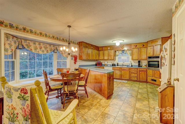 kitchen featuring kitchen peninsula, oven, decorative light fixtures, and plenty of natural light