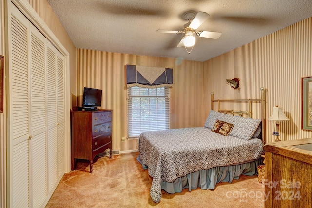 bedroom with ceiling fan, a textured ceiling, and light colored carpet