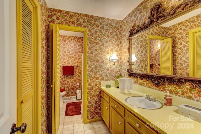 bathroom with toilet, vanity, and tile patterned floors