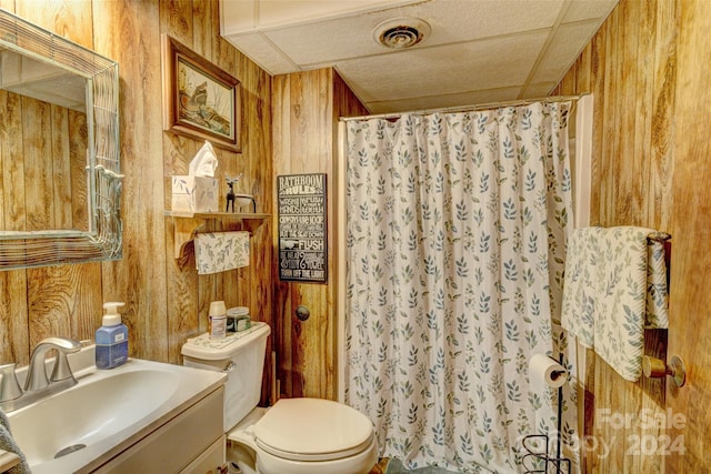 bathroom featuring vanity, wooden walls, toilet, and a shower with curtain