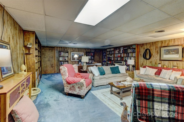 carpeted living room with a paneled ceiling and wooden walls