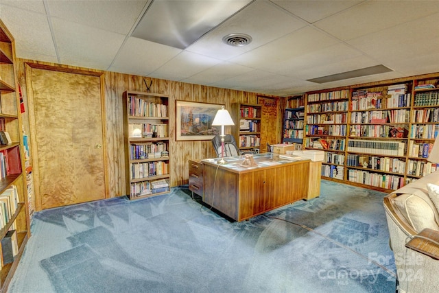 office space featuring wood walls, dark colored carpet, and a drop ceiling