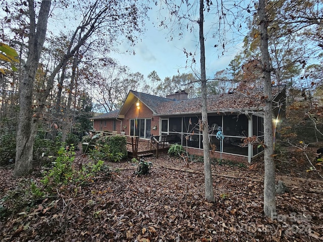 rear view of property featuring a sunroom and a deck