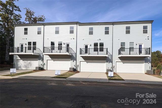 back of house featuring a garage, cooling unit, and a balcony