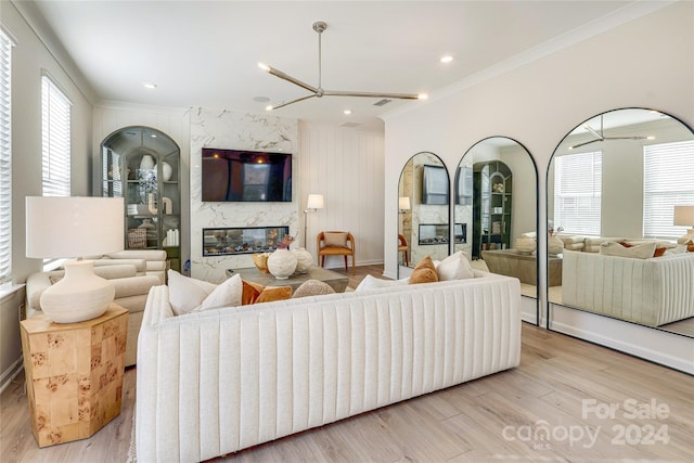 living room featuring a premium fireplace, plenty of natural light, light wood-type flooring, and crown molding