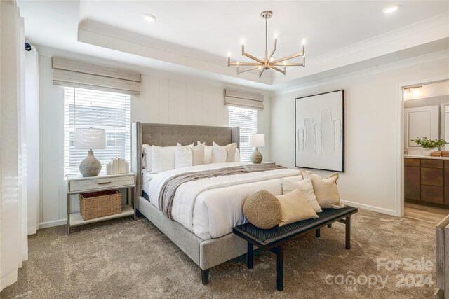 bedroom featuring an inviting chandelier, light carpet, a raised ceiling, and connected bathroom