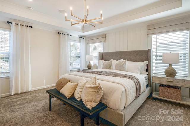 carpeted bedroom with a tray ceiling, multiple windows, and a notable chandelier