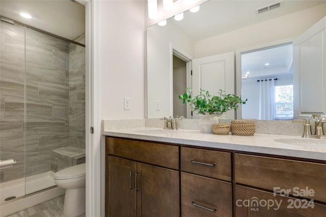 bathroom with toilet, vanity, and a shower with shower door