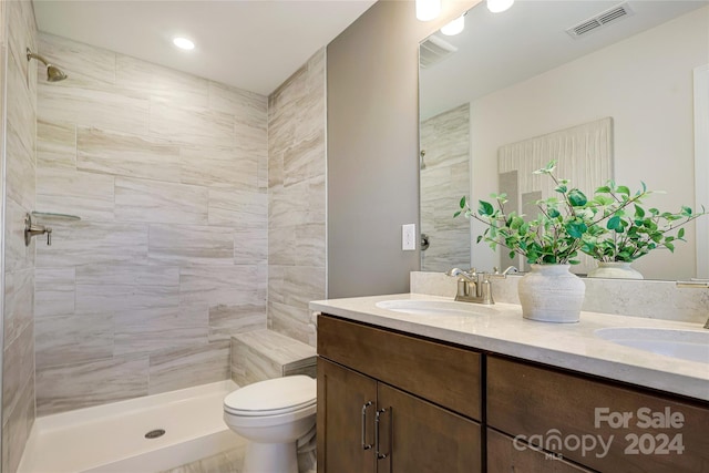 bathroom with a tile shower, vanity, and toilet