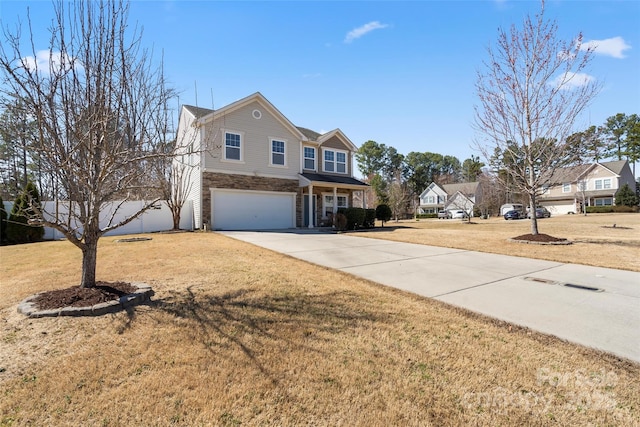 traditional home with an attached garage, driveway, stone siding, and a front yard