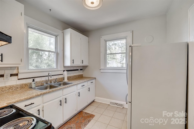 kitchen featuring light countertops, visible vents, electric range, freestanding refrigerator, and white cabinetry