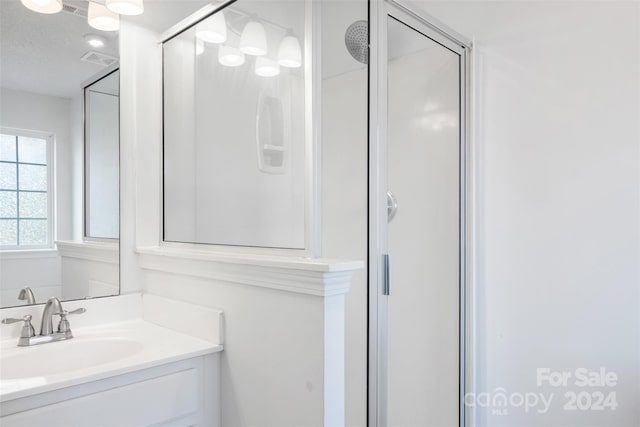 bathroom with vanity, a textured ceiling, and a shower with door